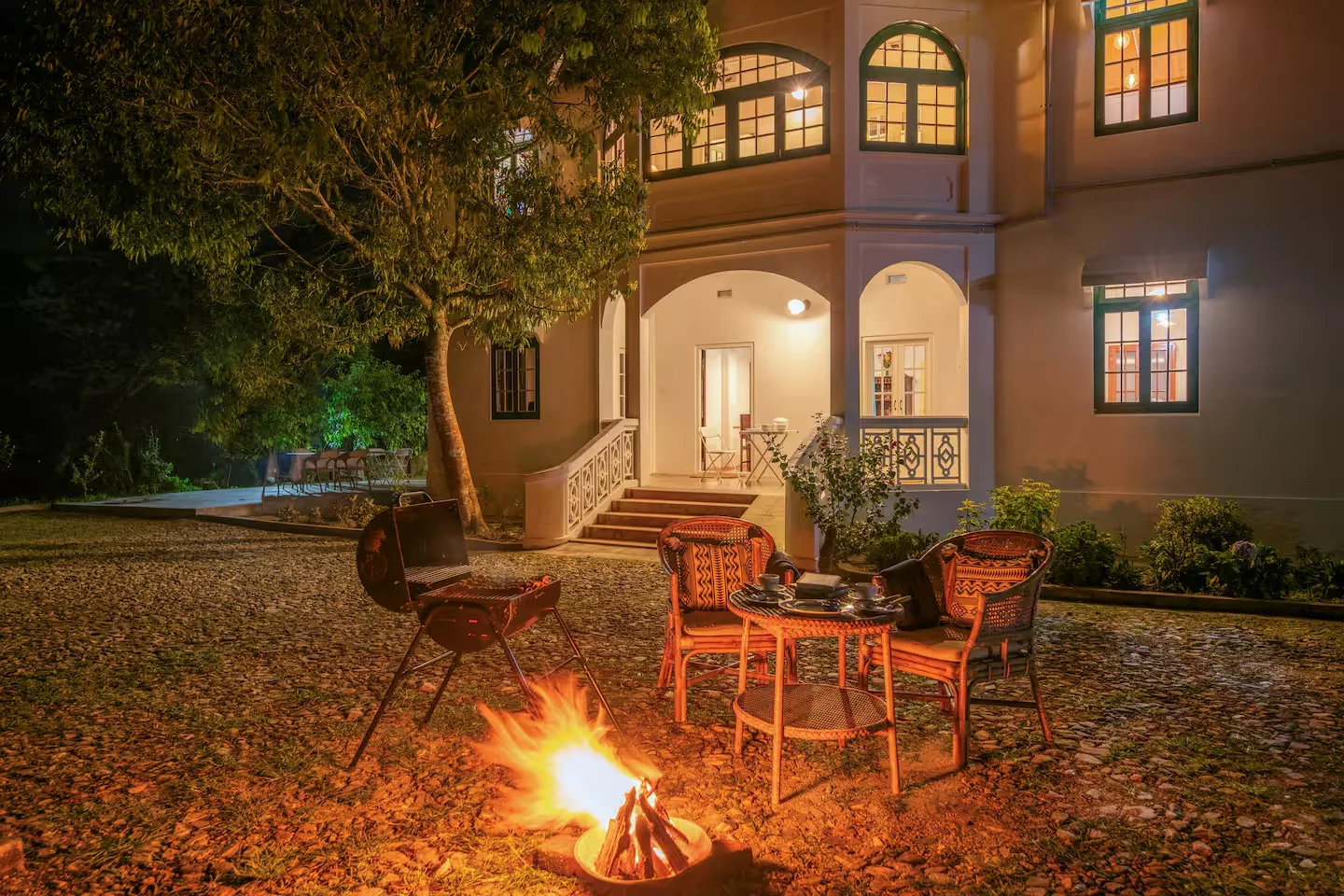 A bonfire burning in the courtyard of the house at night with chairs pulled around it