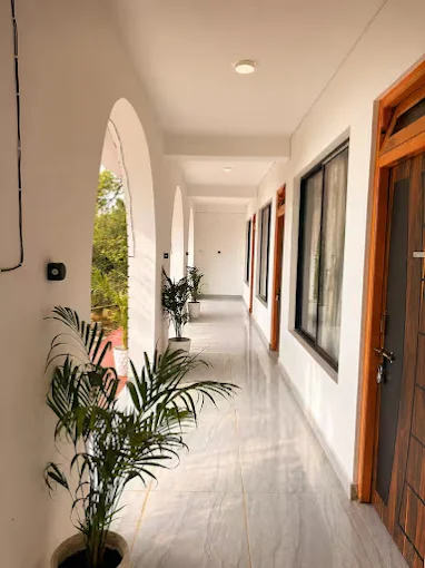 An arched corridor running along the guest rooms, potted plants and wooden doors