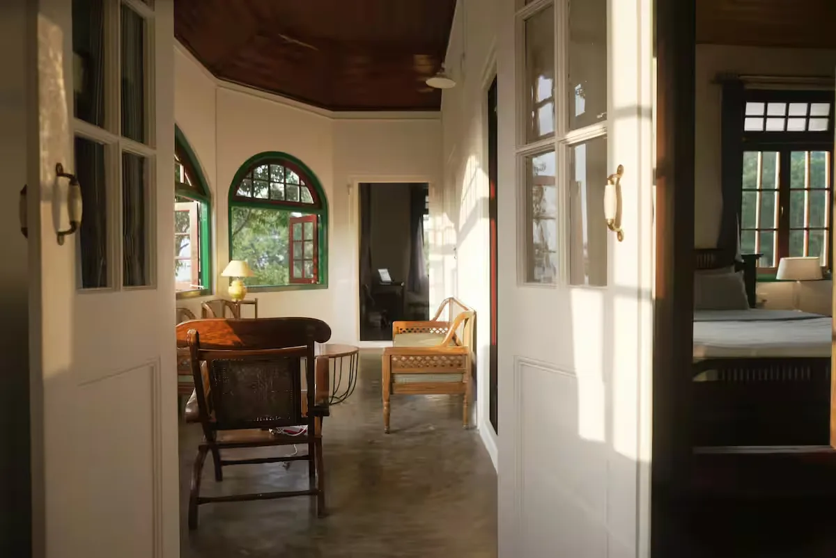 The veranda of the house, arched green-framed windows and cane chairs on a polished floor